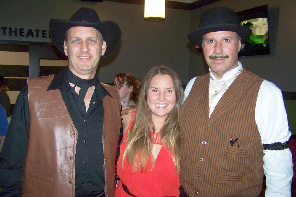 Alamo Drafthouse franchisees Marc Evans, left, and John Martin are in costume to celebrate one year in Springfield with Kiley Haynes, center, of the Springfield Area Chamber of Commerce.
